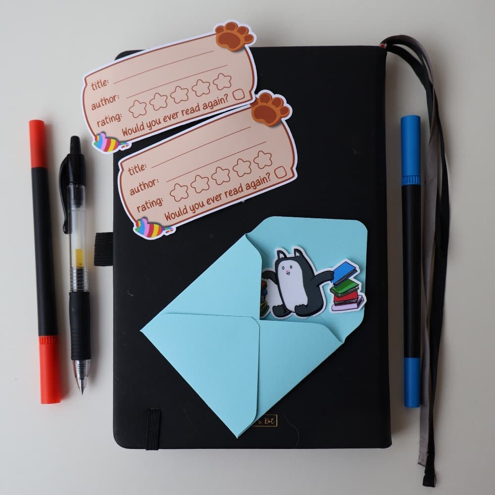 Two book-rating labels and a Pumpkin and Tootsie sticker envelope resting on a notebook